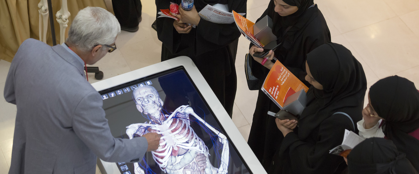 High school students at Medicine Unlimited inspect WCM-Q's hi-tech anatomage table.