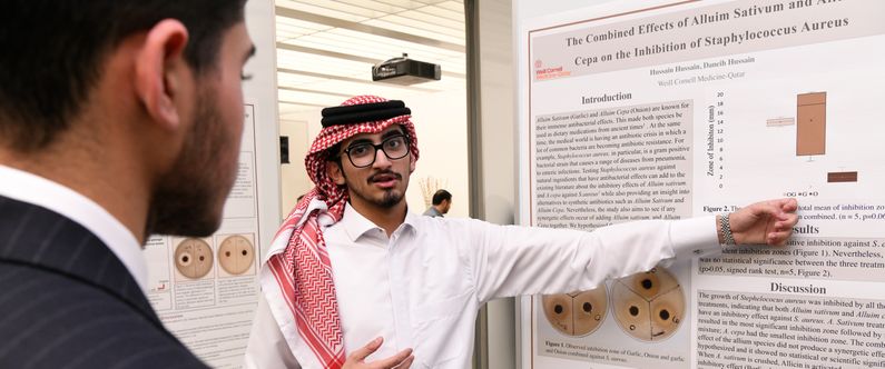Pre-med 1 student Hussain Hussain explains the findings of his research at the poster session.