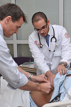 Dr. Liam Fernyhough and first-year medical student Hisham Abdelwahab examine a patient during the student visit to HMC Heart Hospital.