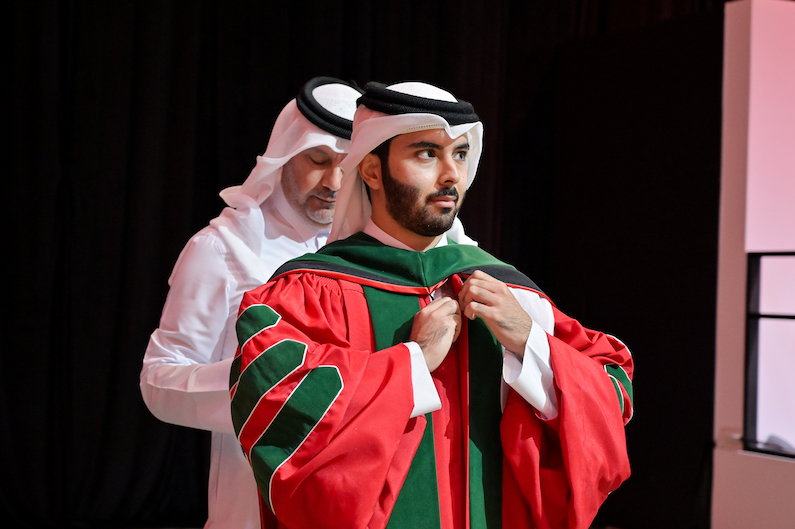 Dr. Abdulla Al-Ansari, Associate Professor at WCM-Q, Deputy Chief Medical Officer for Surgical Services and Medical Advisor for the Managing Director at HMC, places the academic hood upon his son, Dr. Ahmad Abdulla Al-Ansari, at the Graduation Ceremony of the WCM-Q Class of 2026.