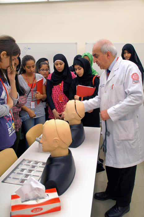 Dr. Verjee demonstrates how to examine a patient's ear to students in the Qatar Future Doctors program.