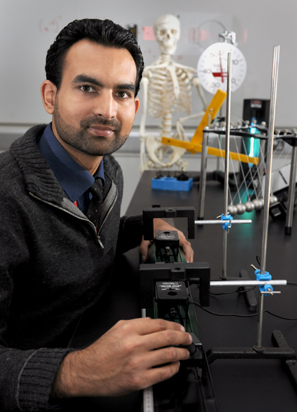 Syed Hasnain, WCMC-Q senior physics lab assistant, with a lab experiment to show Newton's Third Law.