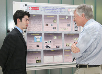 First-year medical student Anas Abou Ismail explains to professor of physics, Dr. Roger Hinrichs, how his desire to pursue a career in research was strengthened over the summer.